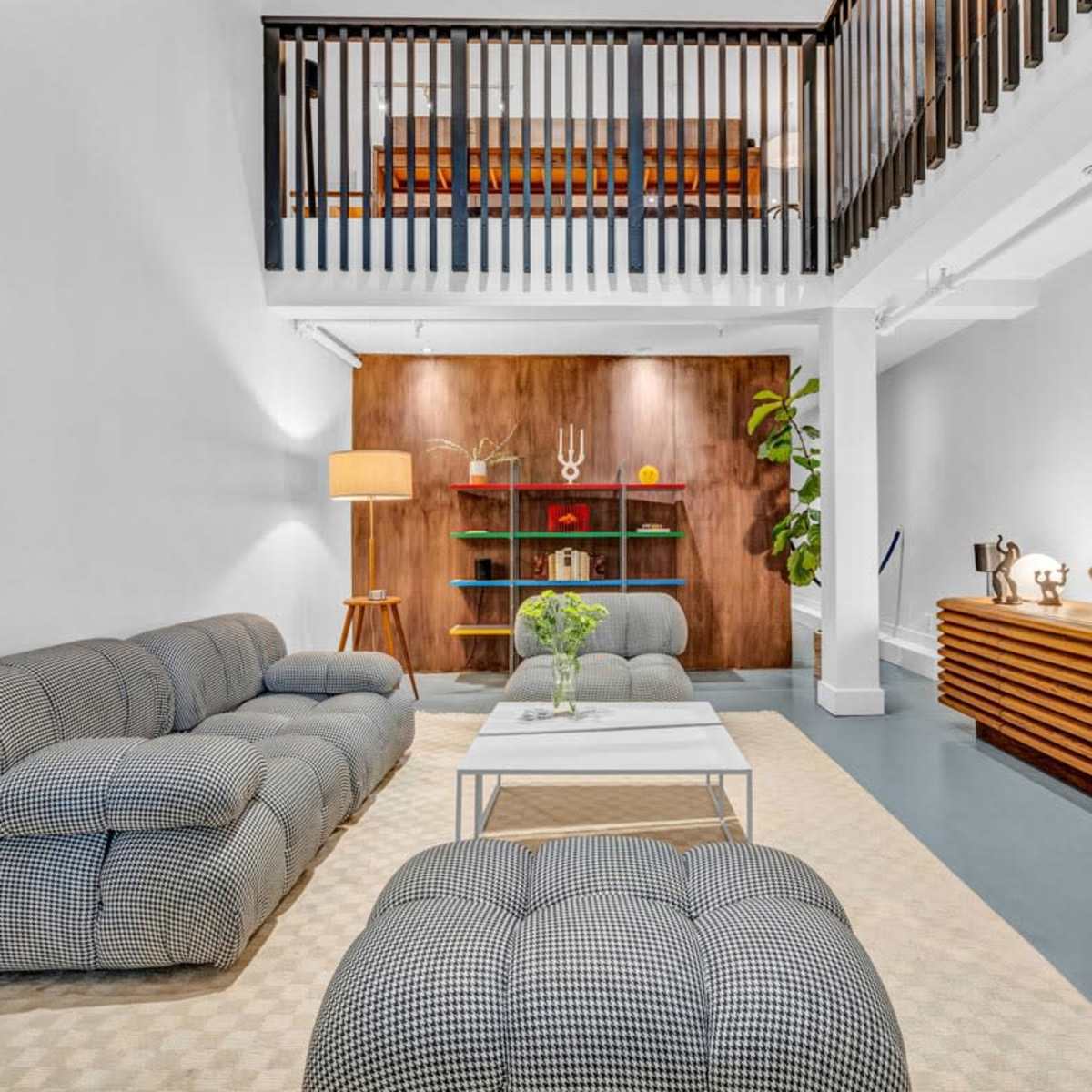 A modern living room with a patterned sofa, a coffee table, and a wooden sideboard, complemented by a decorative wall and plants.