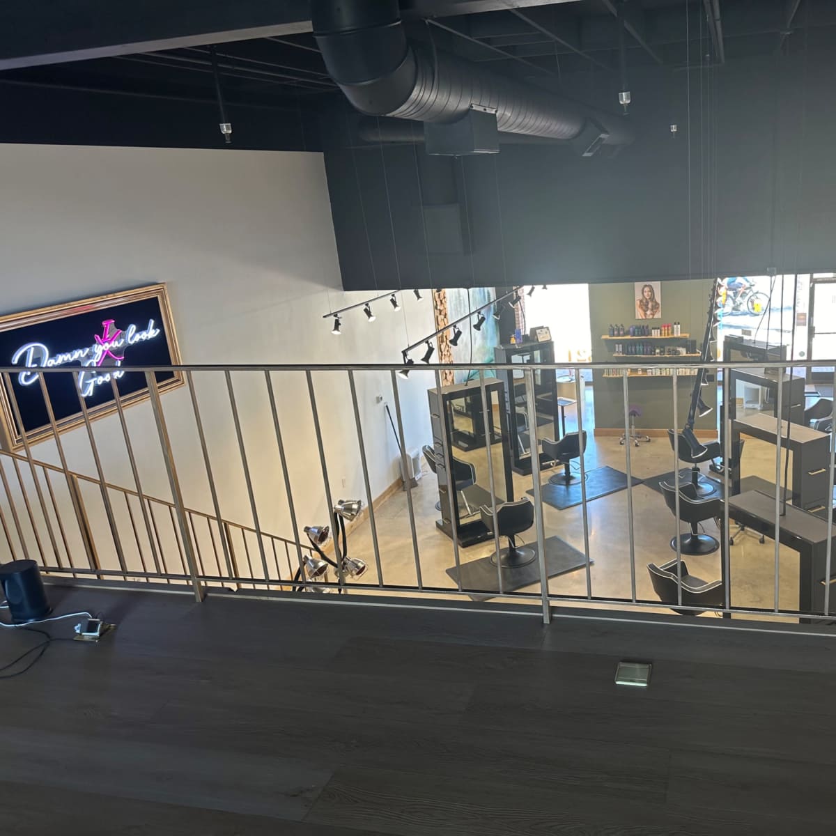 An elevated view of a hair salon featuring several styling stations, black chairs, and bright lighting.