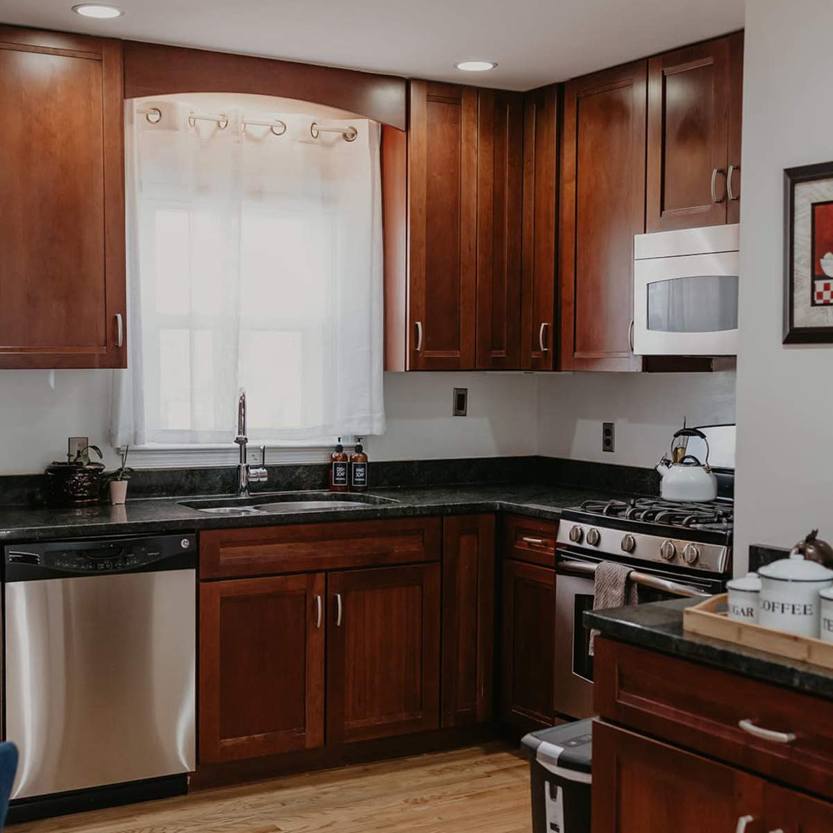 The kitchen features wooden cabinetry, a stainless steel dishwasher, and a black countertop with an oven and a microwave.