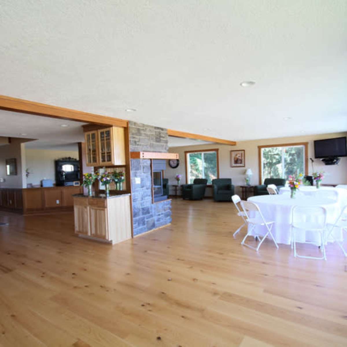 The interior features an open-layout space with a dining area set for eight and a cozy seating area with green chairs.