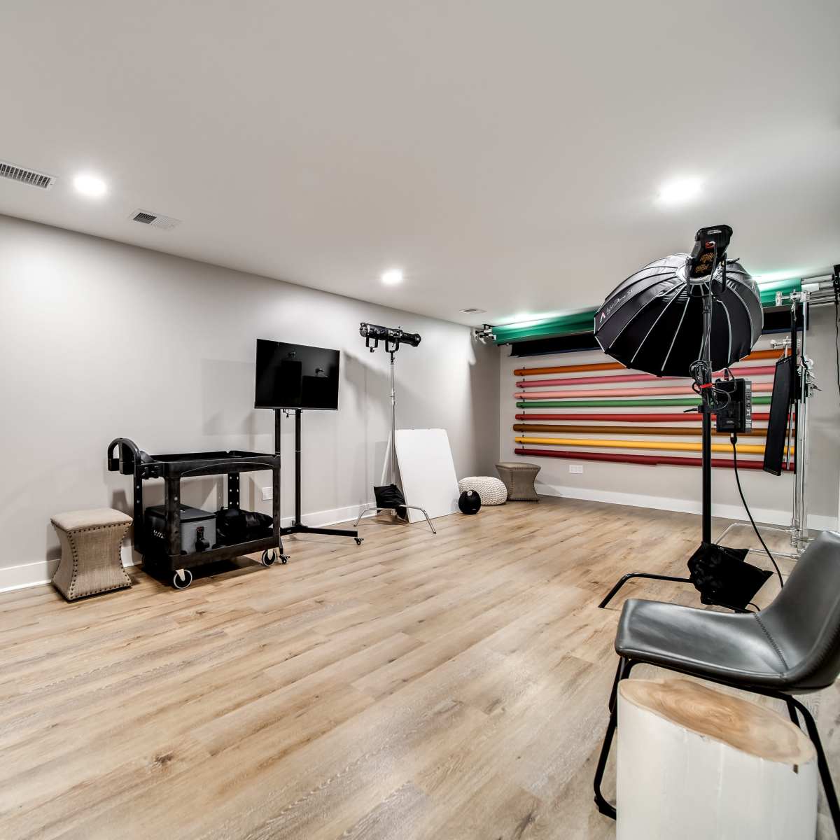 A photography studio with a large backdrop, lighting equipment, and seating arranged along the walls.