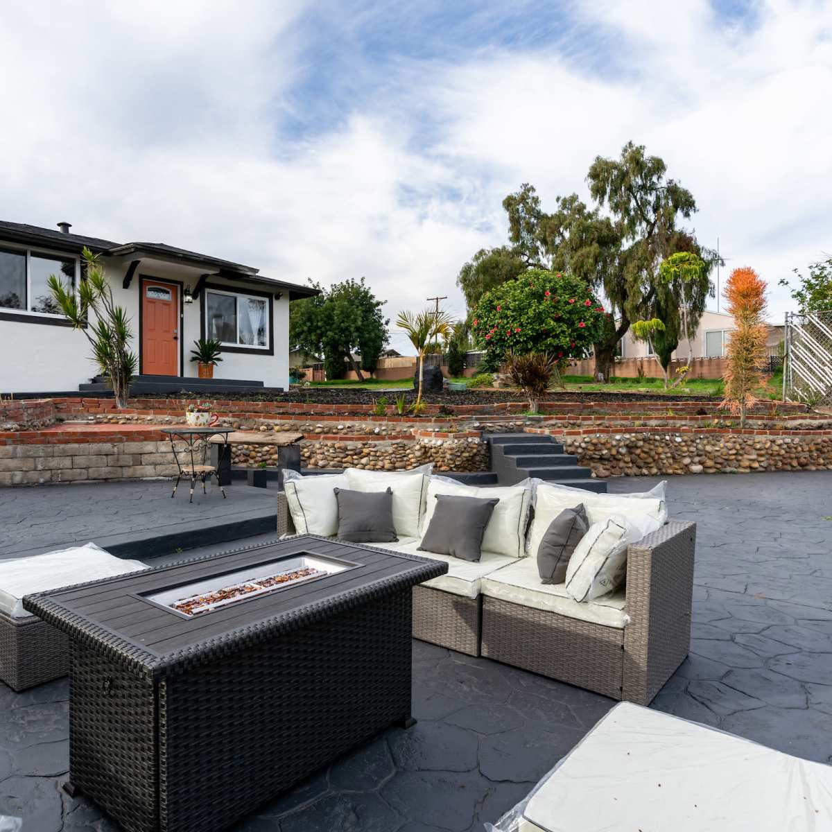 A landscaped outdoor patio area with a seating arrangement and a house in the background.