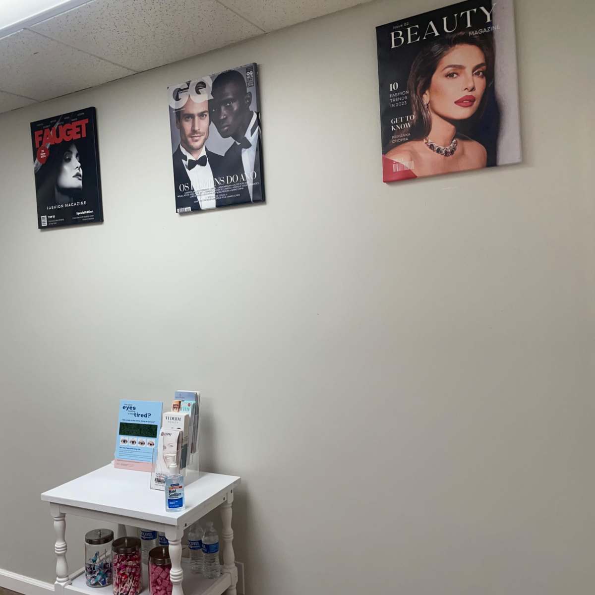 A wall in a waiting area decorated with magazine covers, along with a small table displaying promotional materials.