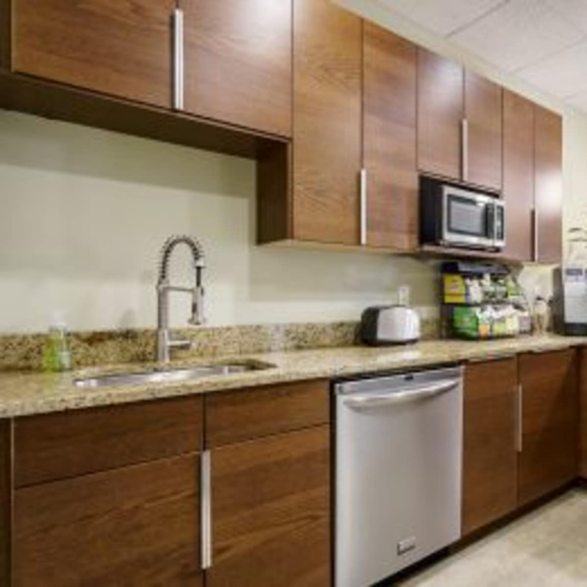 A modern kitchen with wooden cabinets, a stainless steel microwave, and a granite countertop.