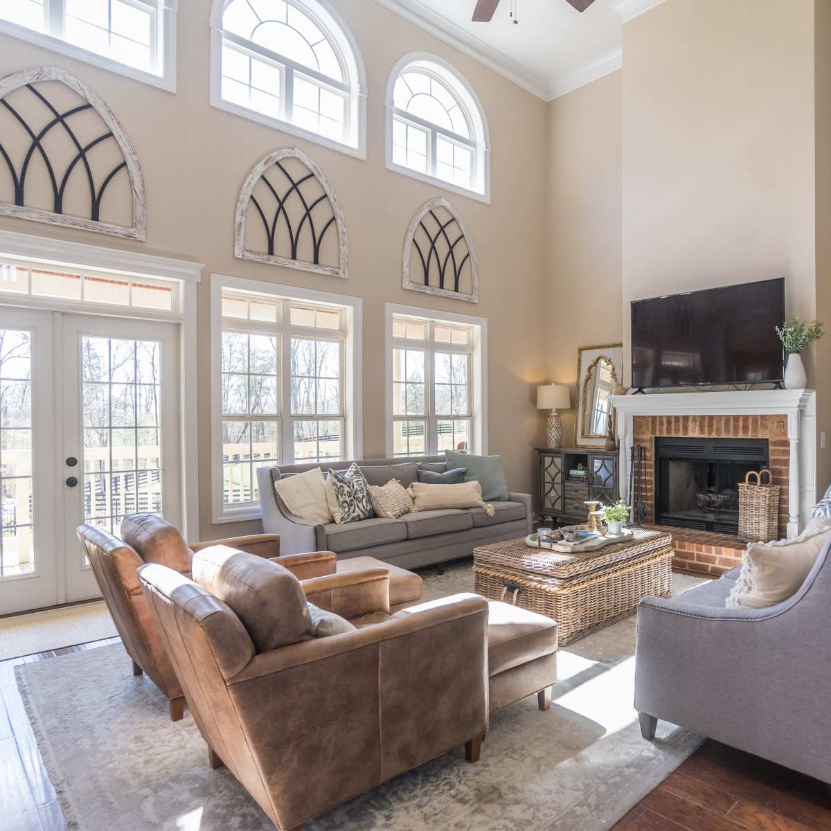 The living room features large windows, two sofas, and a fireplace with decorative elements.