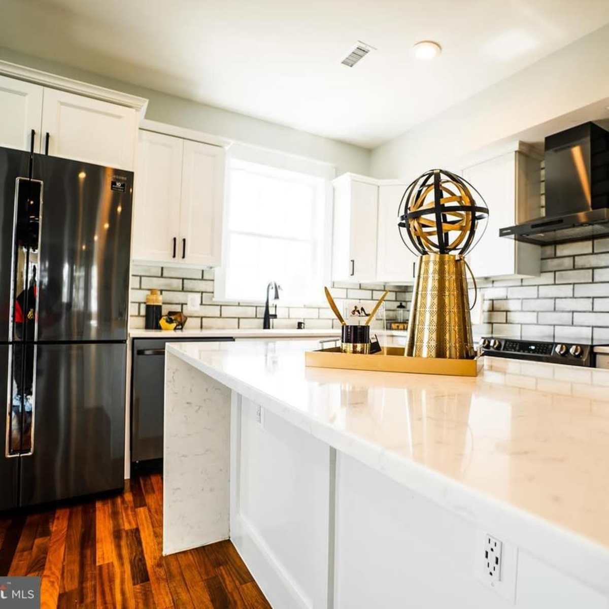 The kitchen features stainless steel appliances, white cabinetry, and a large island with a decorative globe on top.