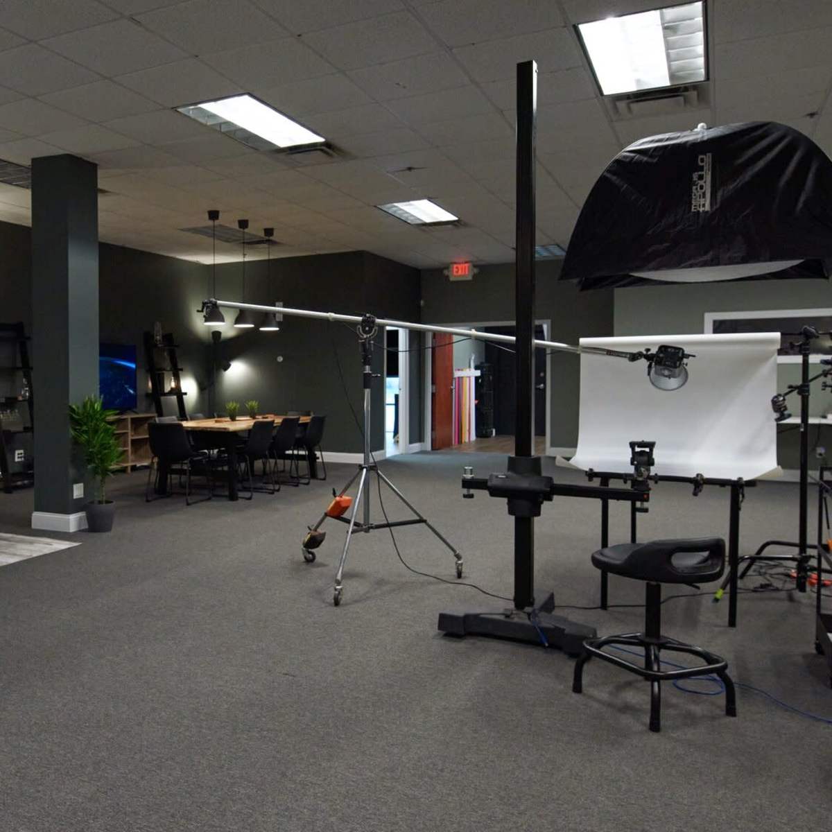 A spacious indoor studio featuring a seating area, a large table, and various photography equipment set up for a shoot.