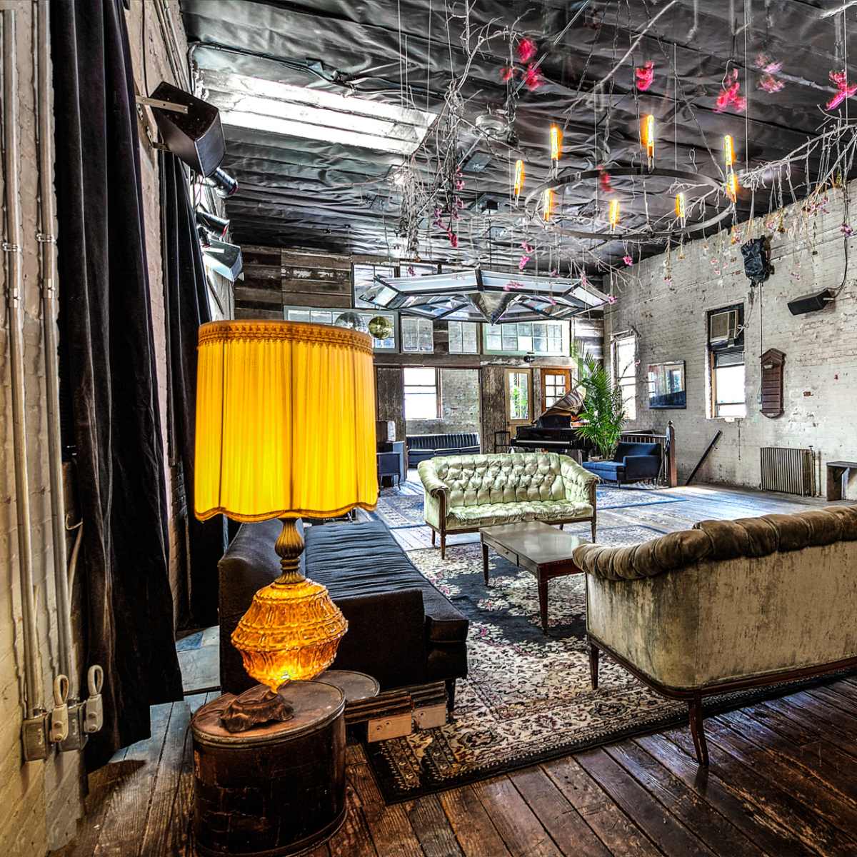 A spacious, vintage-style interior featuring decorative lighting, plush seating, and a mix of textures on the walls and floor.