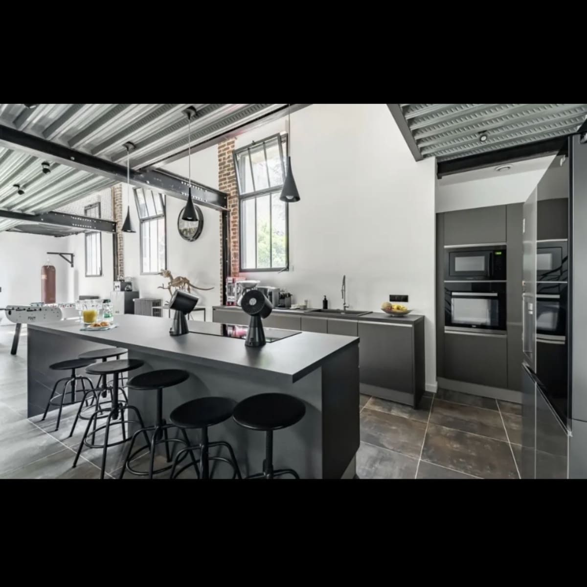 A modern kitchen with a large central island, sleek cabinetry, and industrial-style lighting fixtures.