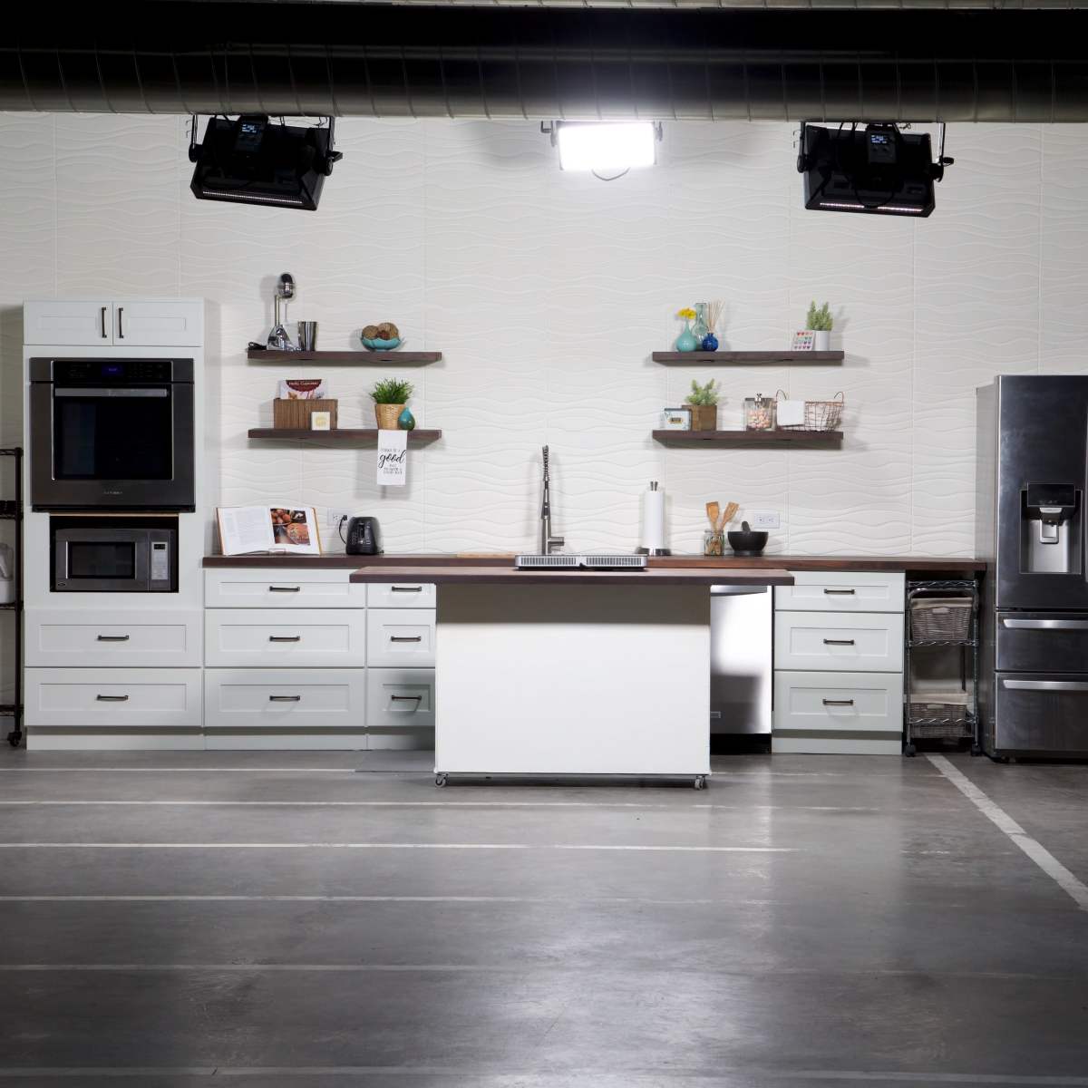 A modern kitchen setup with white cabinets, stainless steel appliances, and open shelves displaying decorative items.