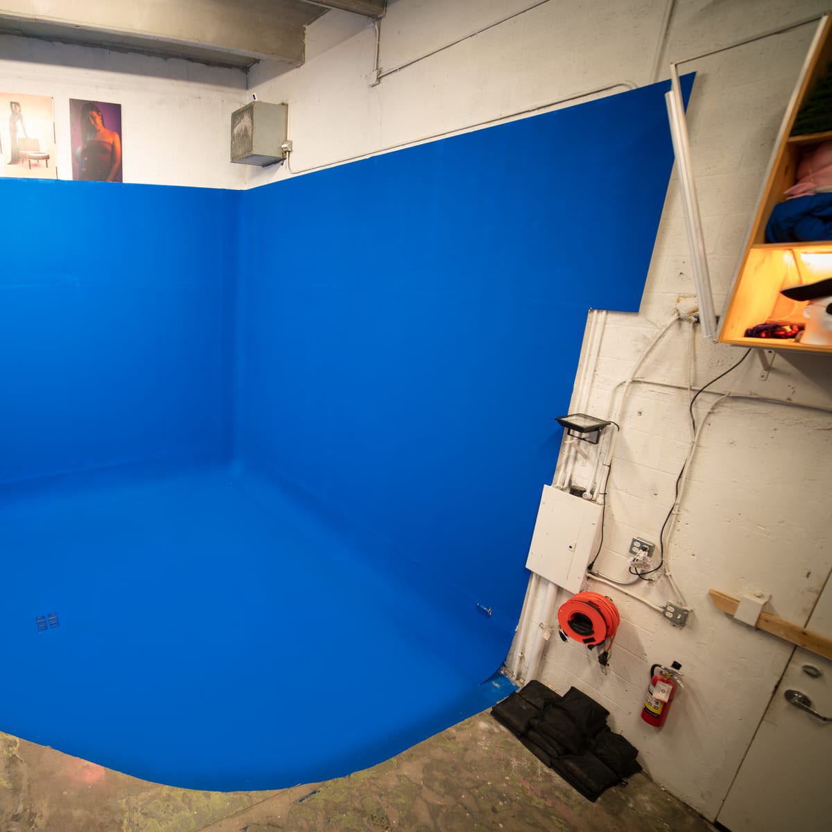 A studio space with a blue backdrop and floor, along with various lighting and equipment on the side.