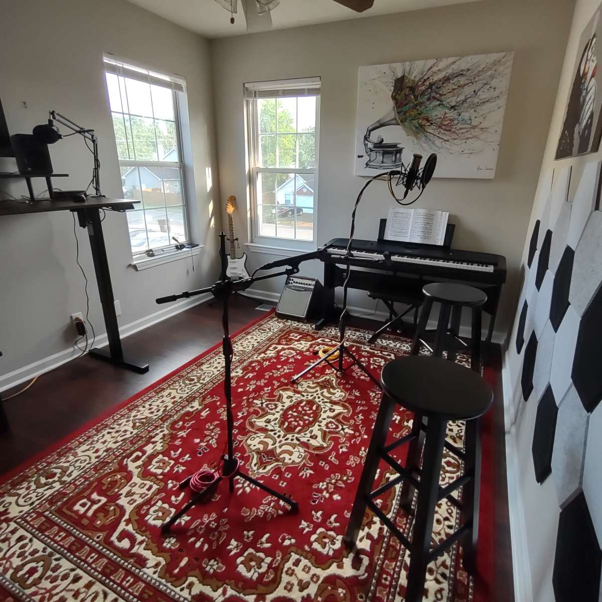 The room features a piano, microphones on stands, and music-related decor against a backdrop of large windows and a patterned rug.
