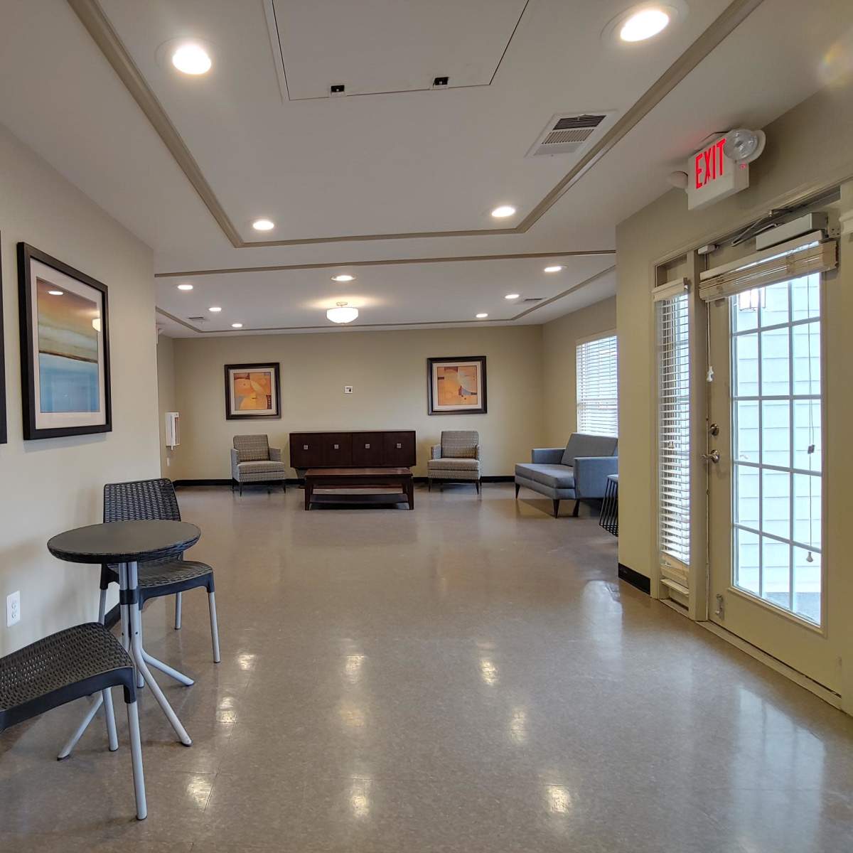 A modern, spacious lobby area with framed artwork on the walls, a seating arrangement, and large windows allowing natural light.