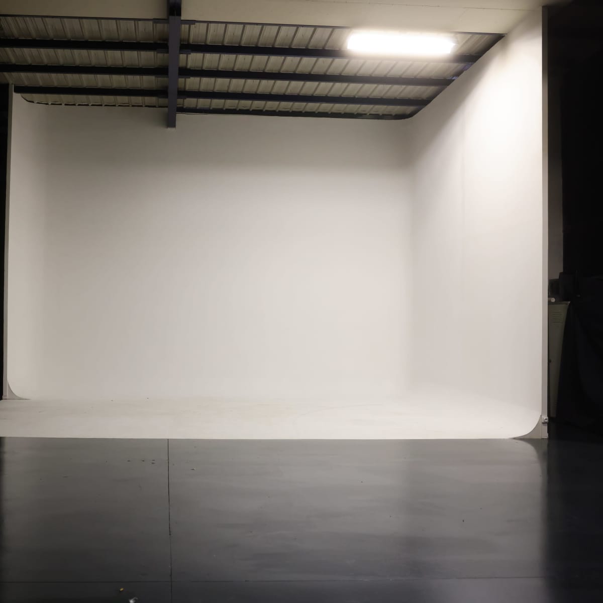 A spacious photography studio with a large seamless white backdrop and a polished dark floor.