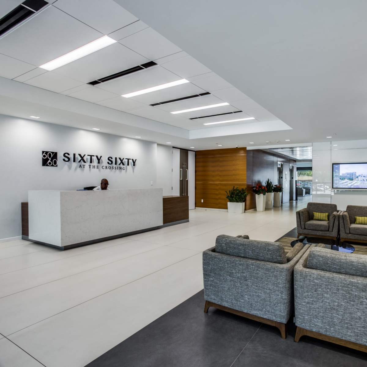 A modern lobby with a reception desk, seating area, and a large artwork on the wall.