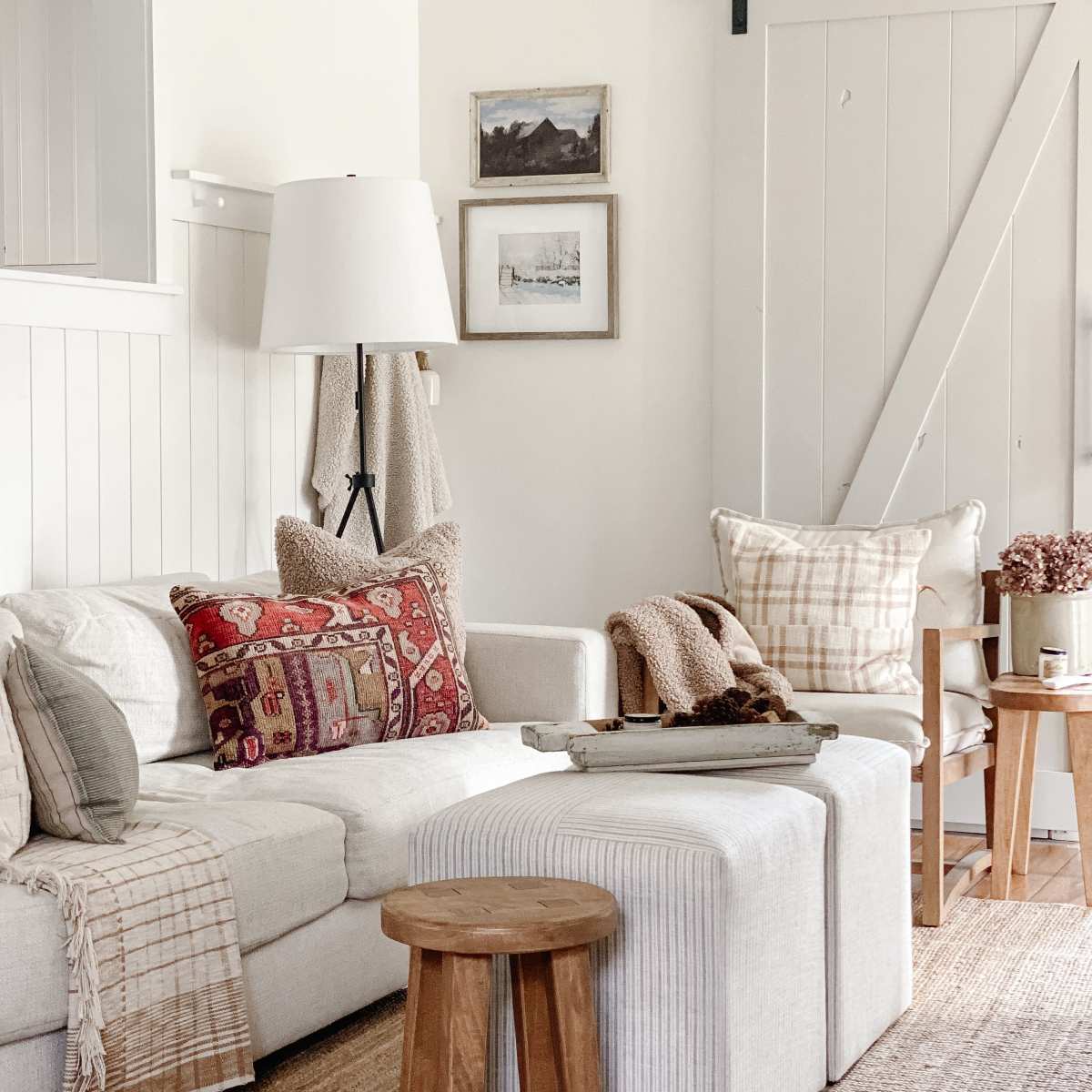 A cozy living room with a light-colored sofa adorned with decorative pillows, a wooden coffee table in the center, and framed art on the walls.