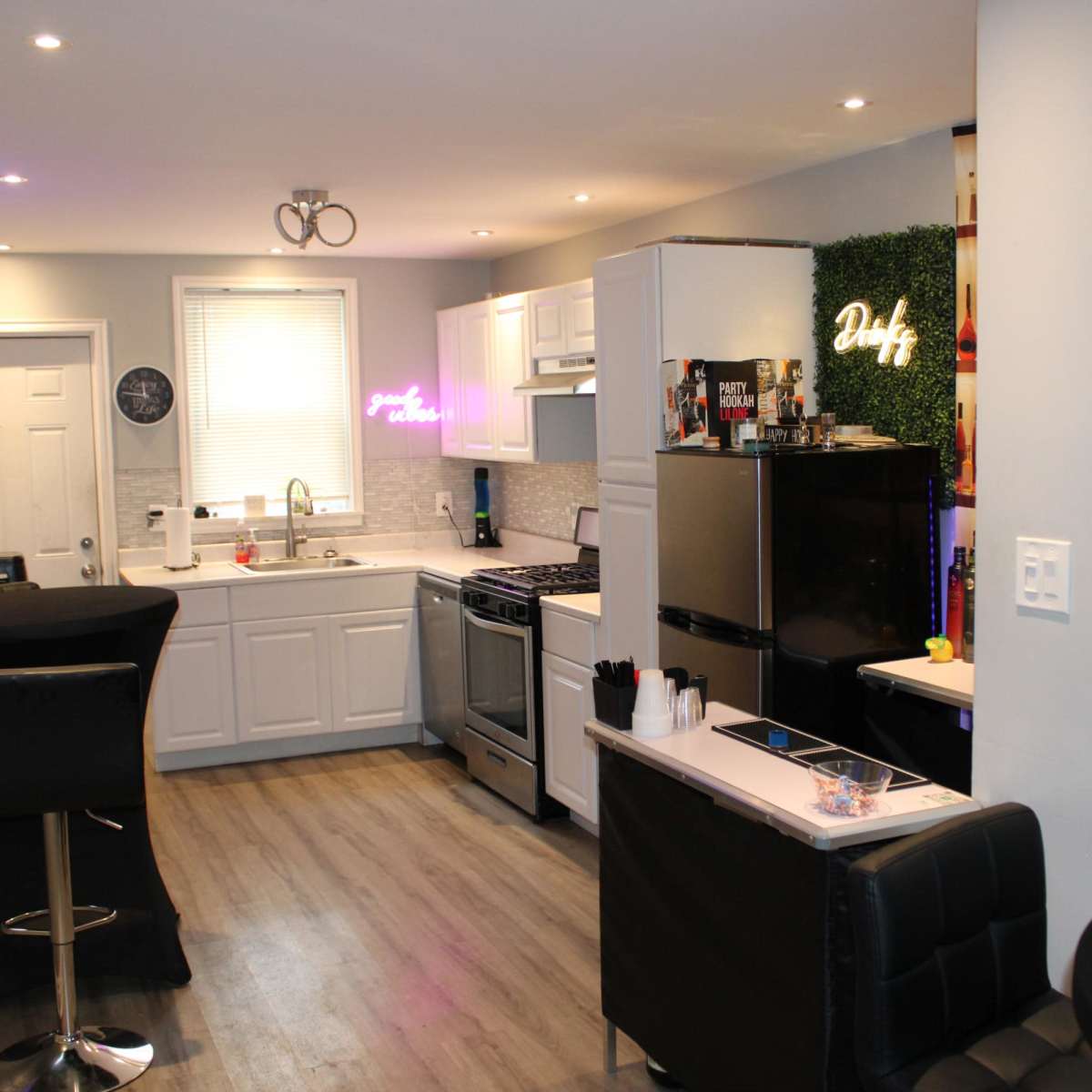 A modern kitchen with white cabinets, stainless steel appliances, and a dark bar area with stools.
