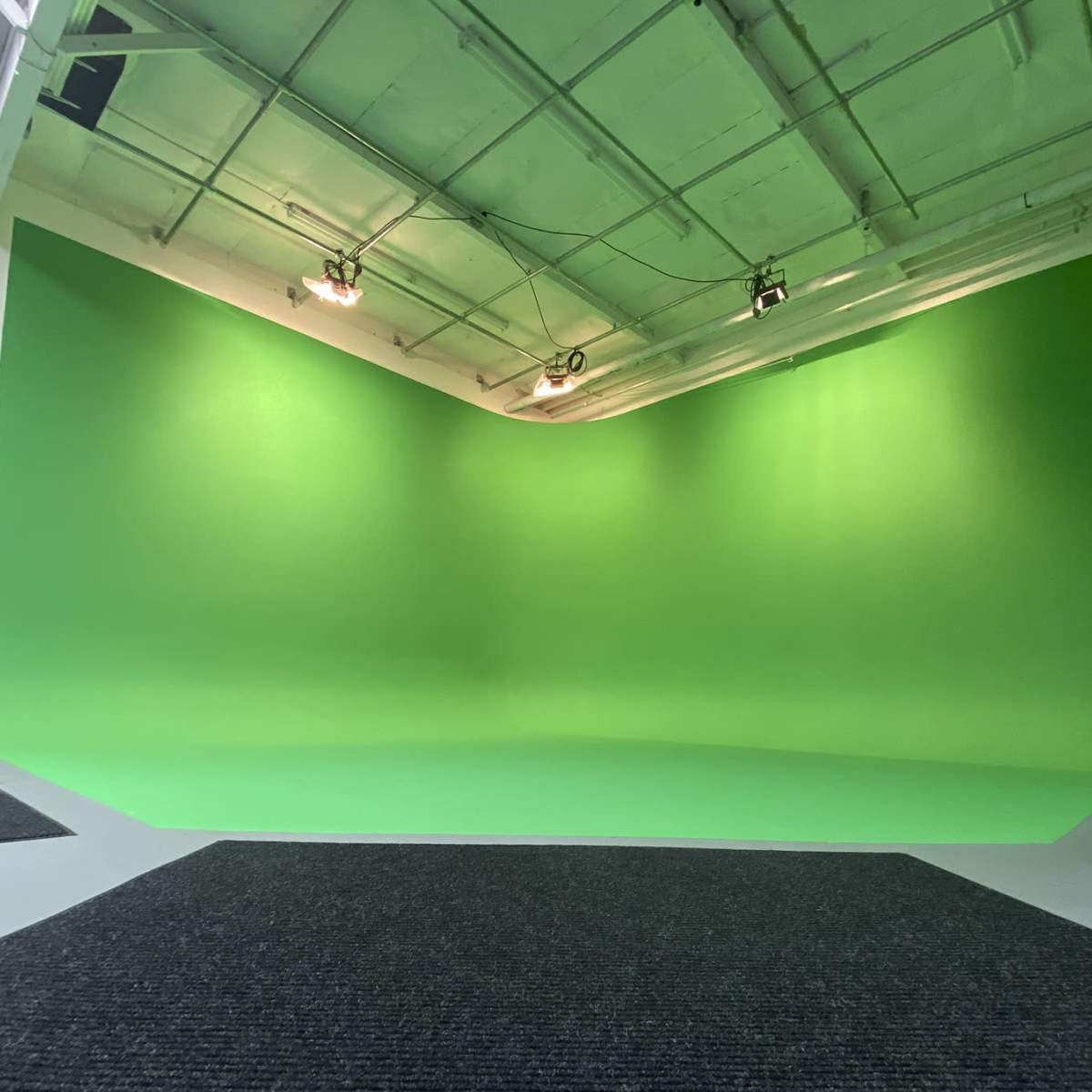 A bright green screen in a studio setting with a textured black mat in front.