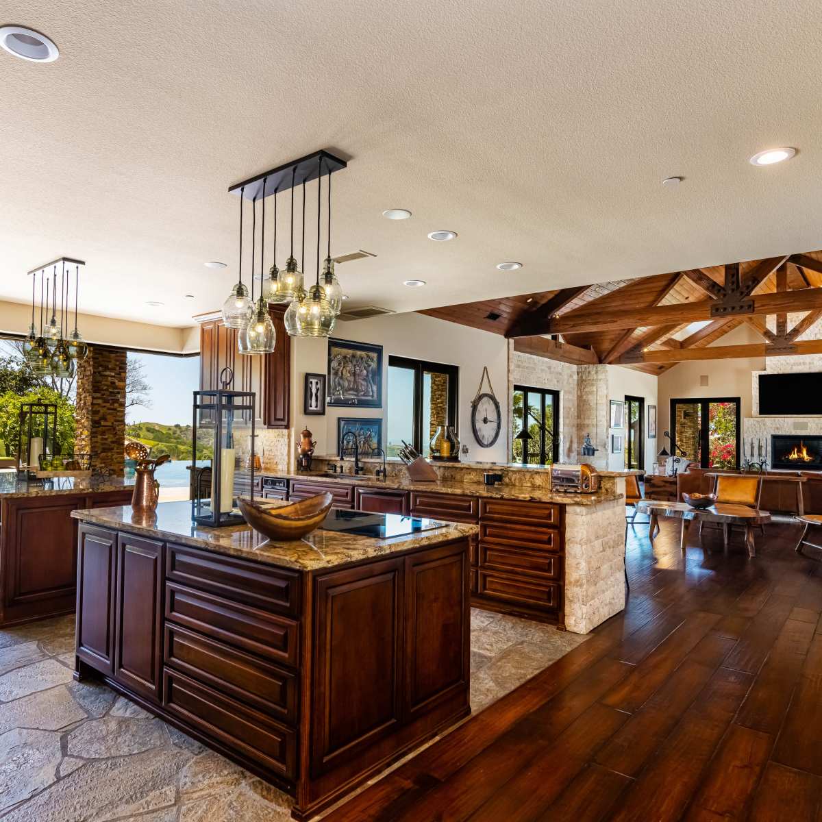 The spacious kitchen features dark wooden cabinets, granite countertops, and large windows that provide a view of the outdoor area.
