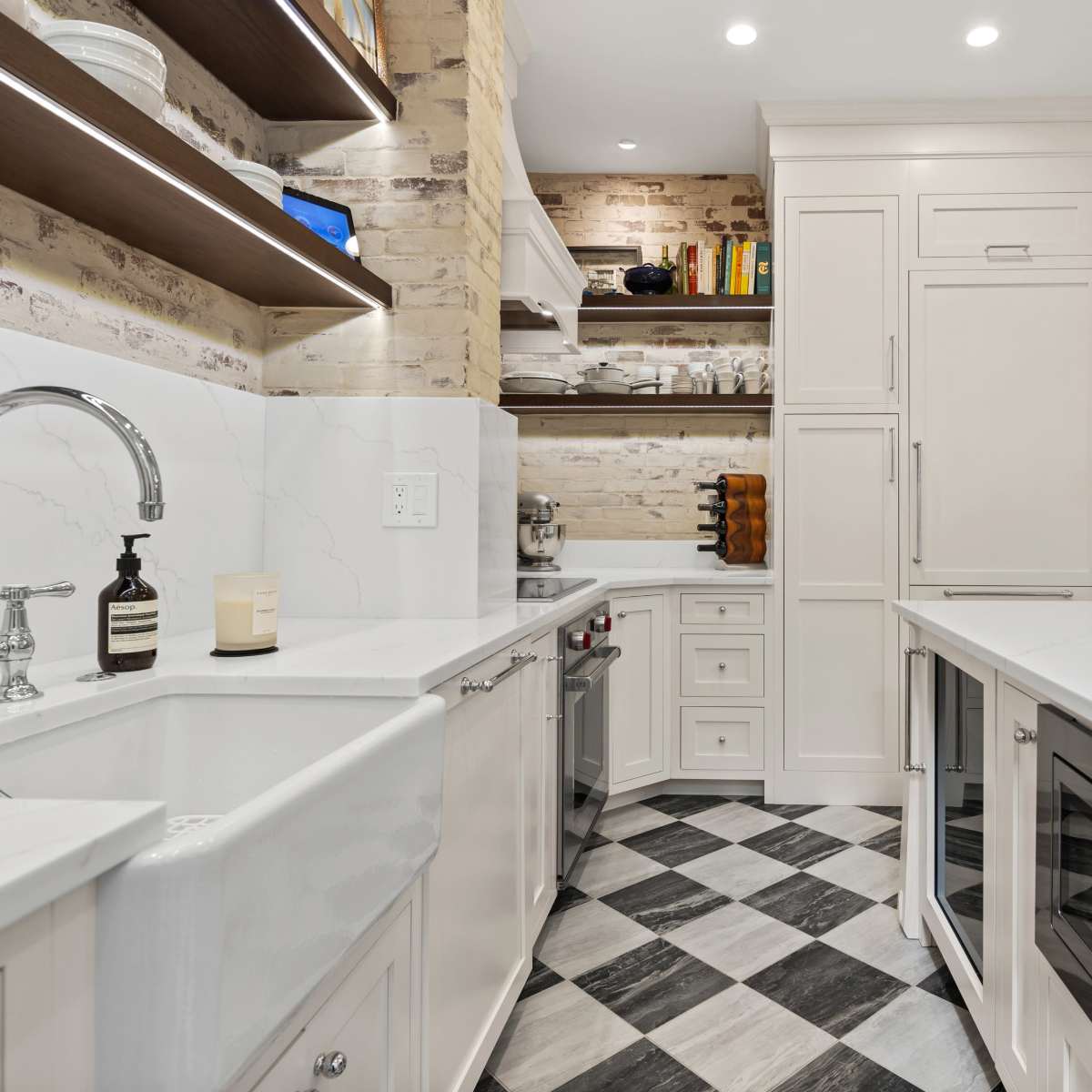 The kitchen features a white marble countertop, a farmhouse sink, and checkered flooring, with shelves displaying neatly arranged kitchenware.