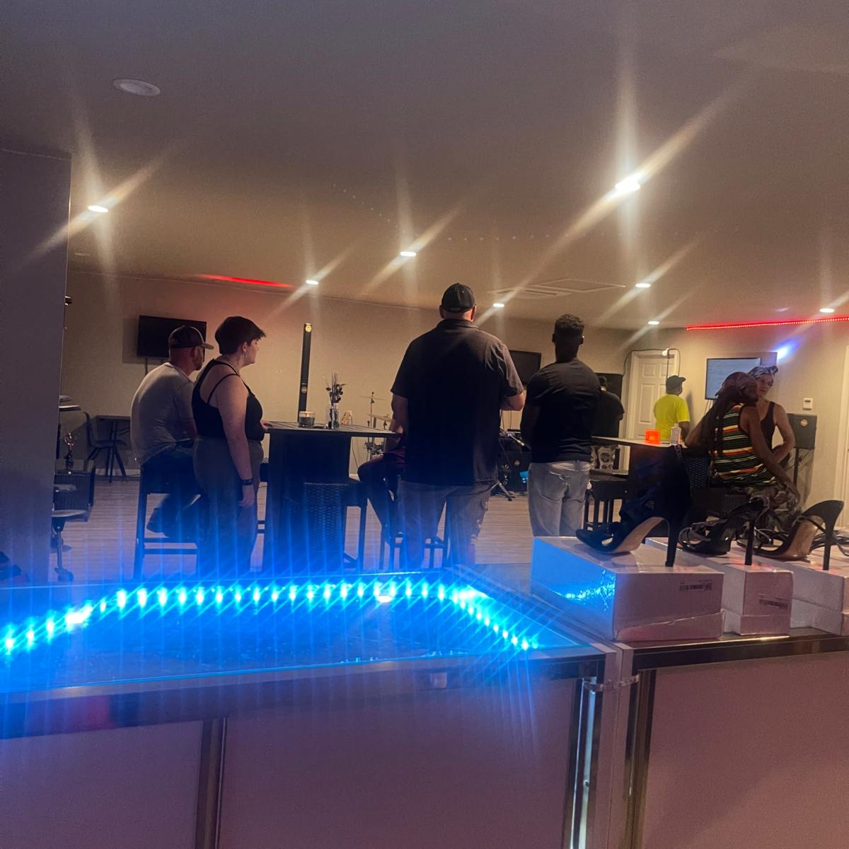 A group of five people stands in a well-lit room with a modern bar area and various tables.