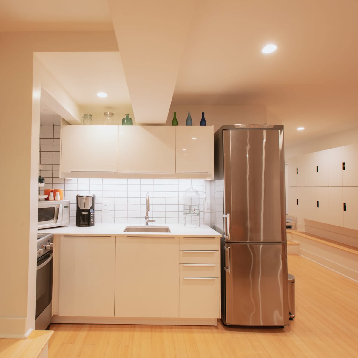 A modern kitchen with white cabinetry, a stainless steel refrigerator, and a countertop with a sink.