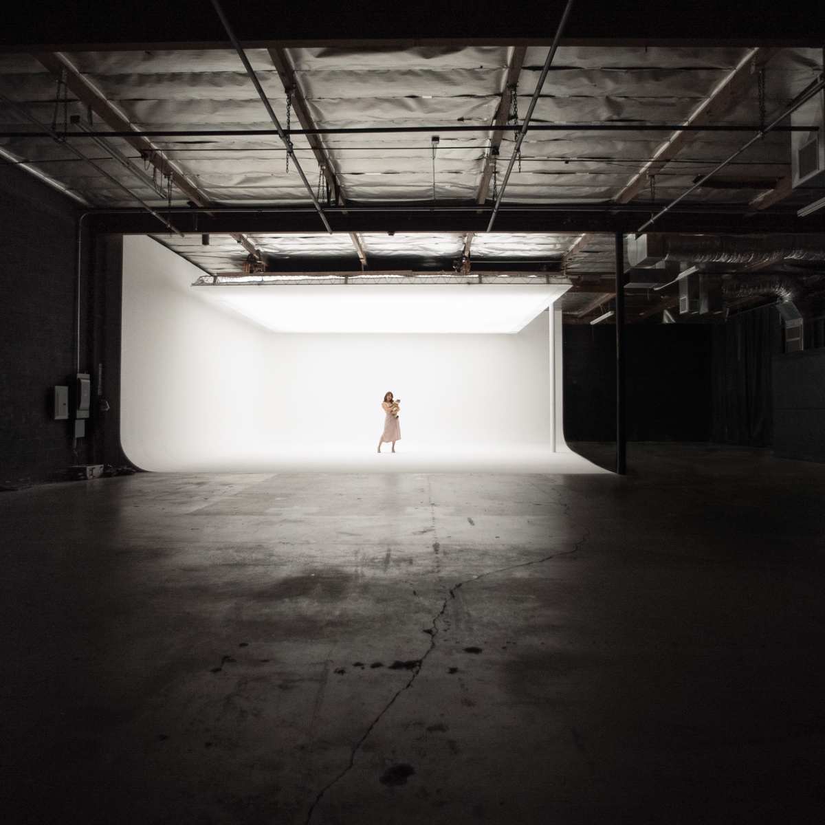 A person stands alone in a well-lit studio space with a white backdrop.