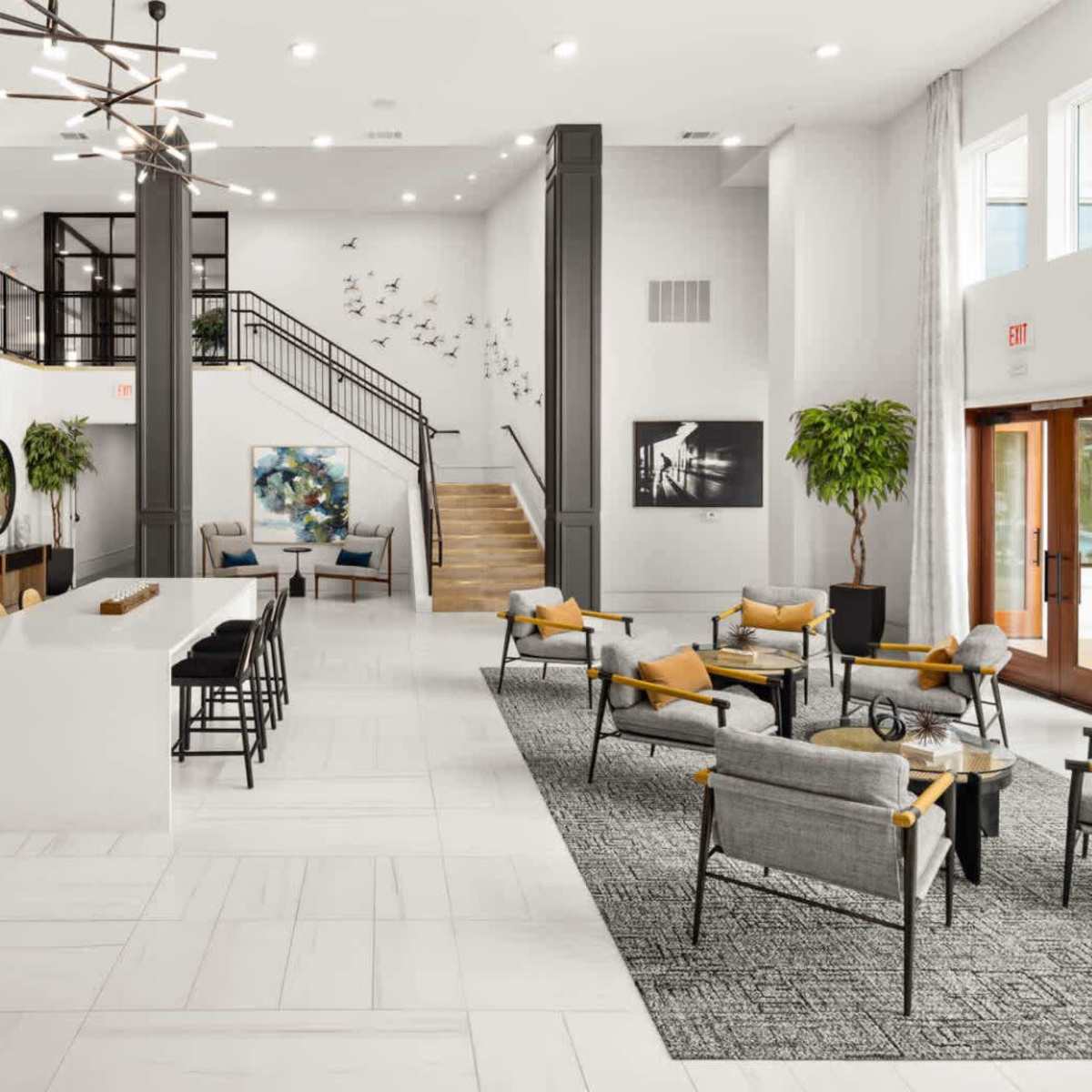 A spacious lobby features a modern check-in area, seating arrangements with yellow accent pillows, and large windows allowing natural light.