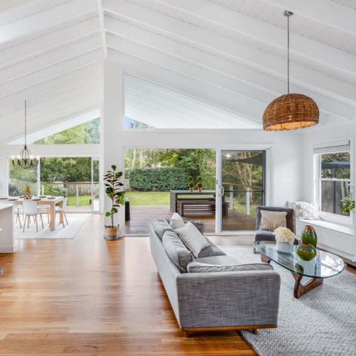 A spacious, open-concept living area features high ceilings, a modern kitchen with bar stools, and large windows that let in natural light.