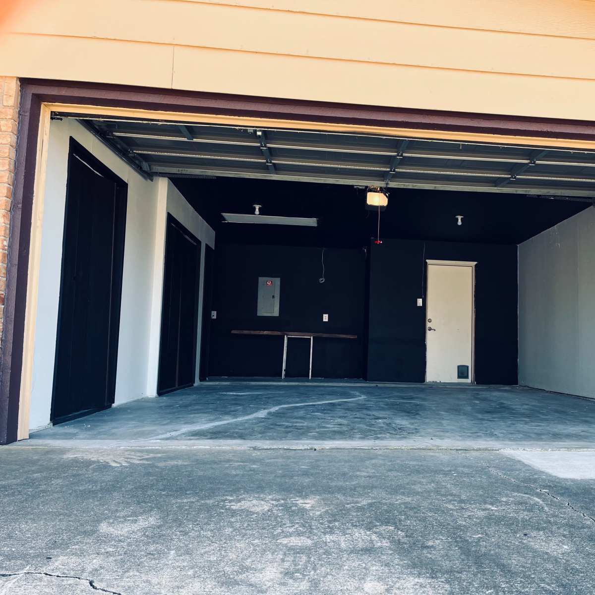 A clean, empty garage with concrete flooring and a single door on the right side.