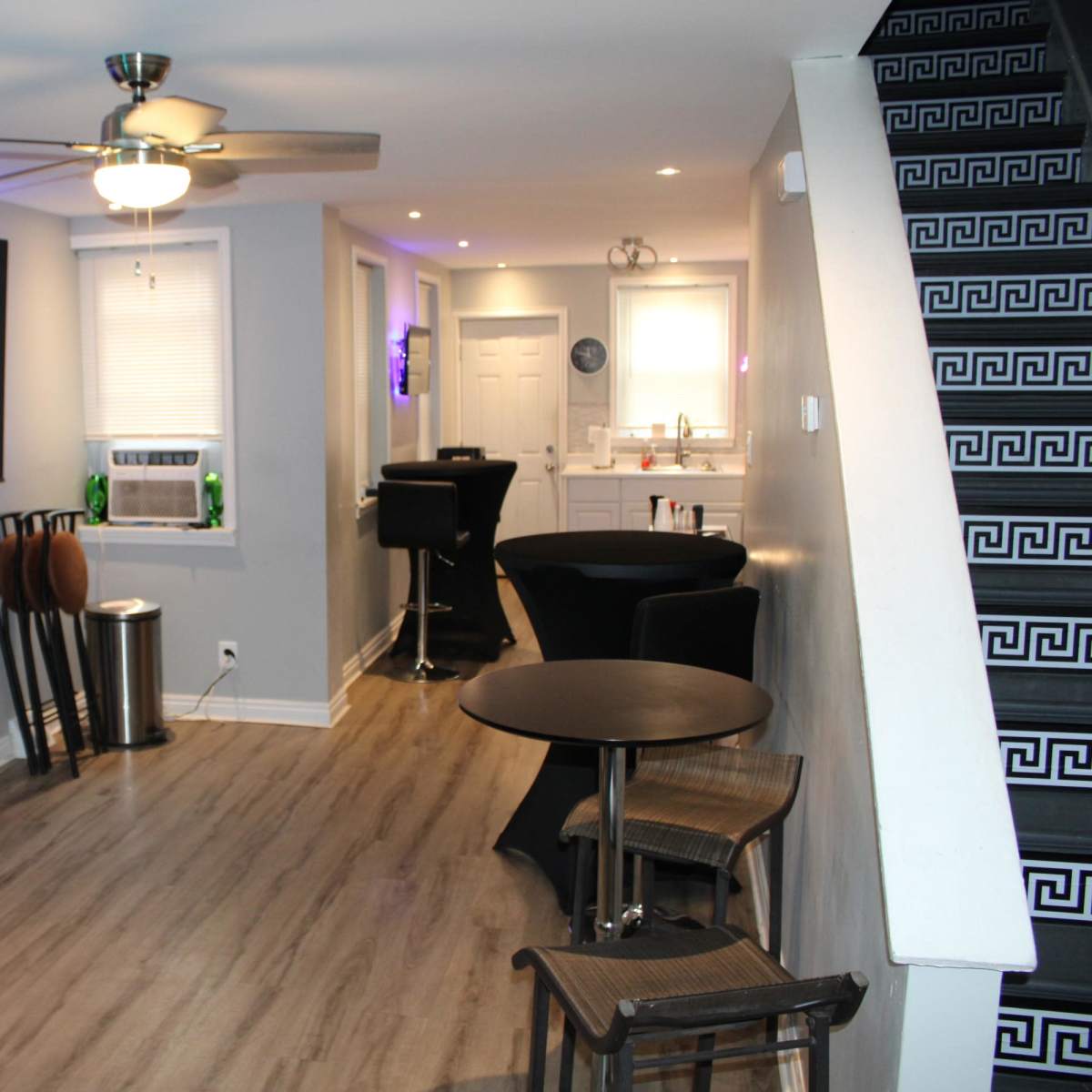 A modern living space with a television mounted on the wall, a bar area, and a staircase with patterned steps.