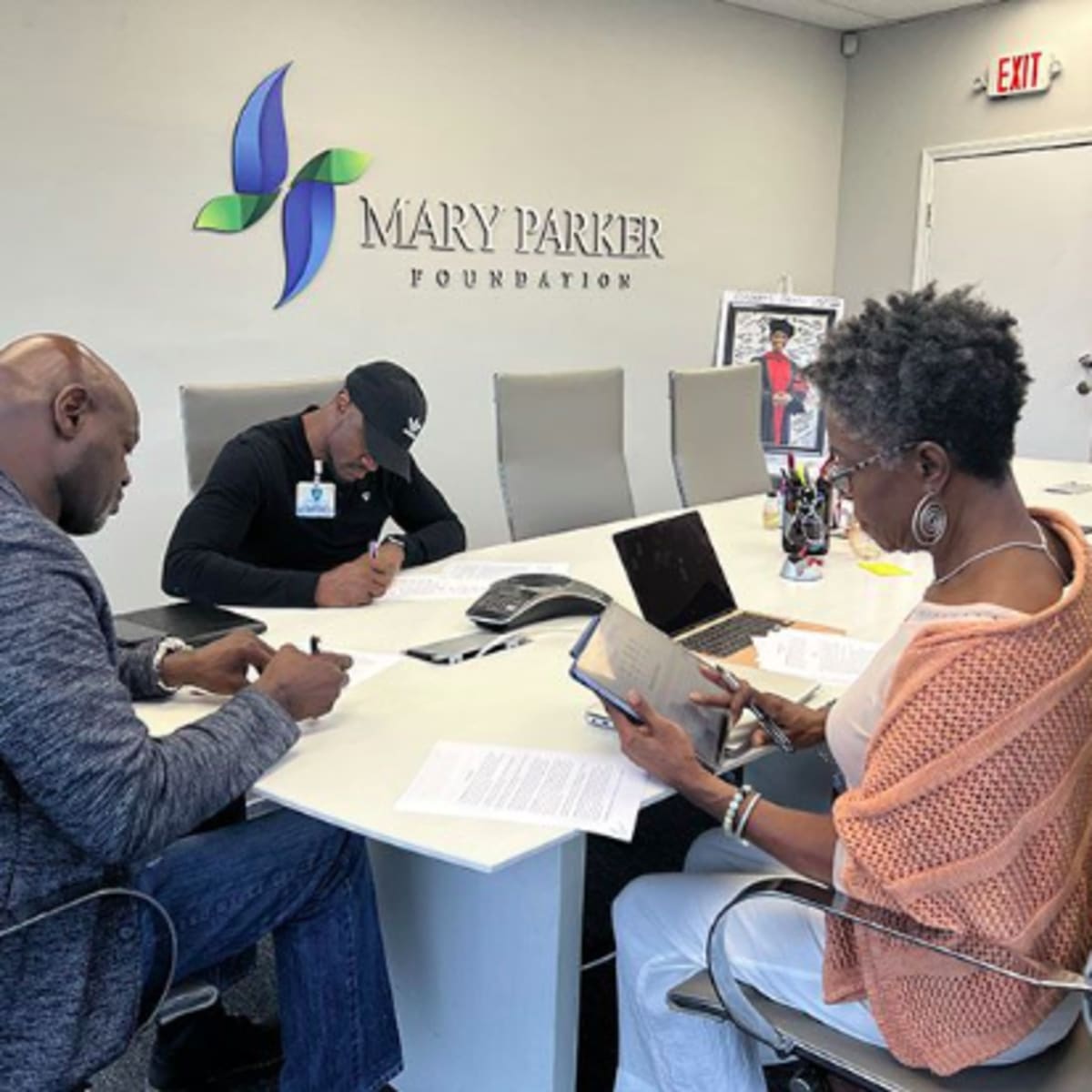 Three people are seated at a conference table in the Mary Parker Foundation office, engaging in discussion and reviewing documents.