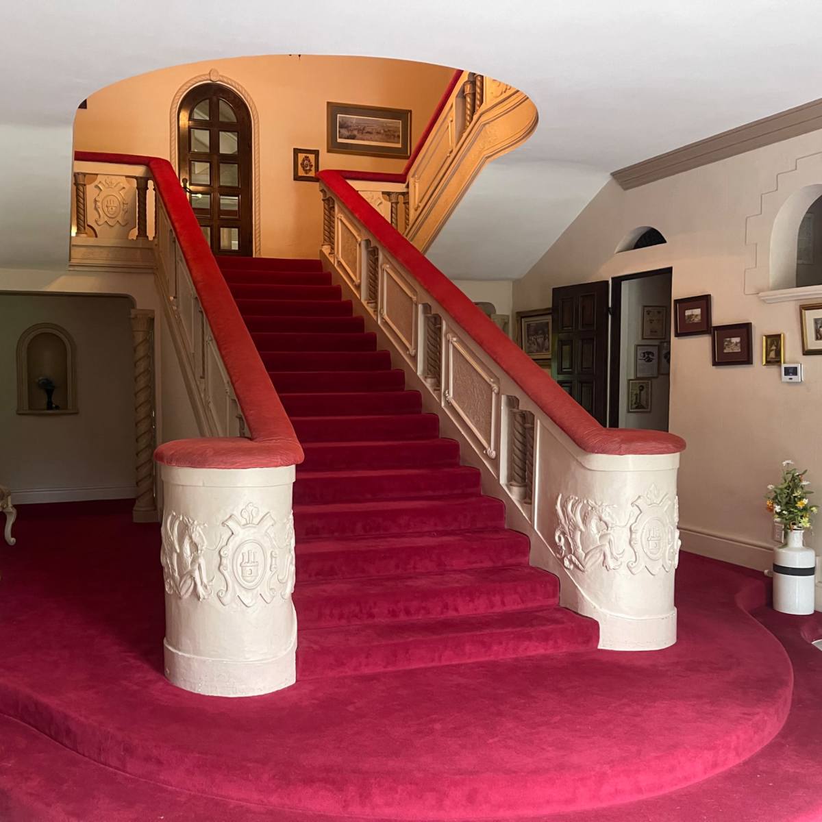 A grand entryway with a red carpet and a curved staircase leading to an upper level.
