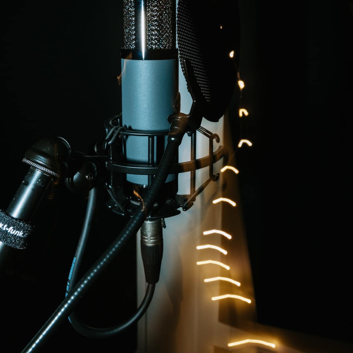 A microphone is positioned in front of a blurred backdrop of glowing lights.