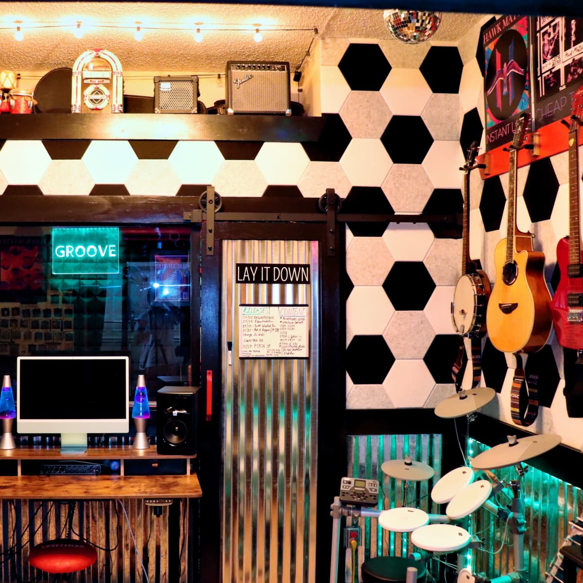 A music-themed room with hexagon-patterned walls, various instruments displayed, a computer setup, and neon lighting.