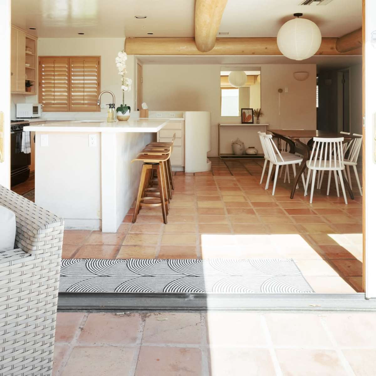 A spacious open-concept kitchen and dining area with tile flooring, visible through a large sliding door.