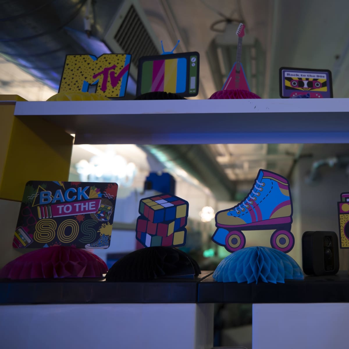 A colorful display of retro-themed decorations on a shelf, including items like a miniature boombox, a roller skate, and a Rubik's cube.