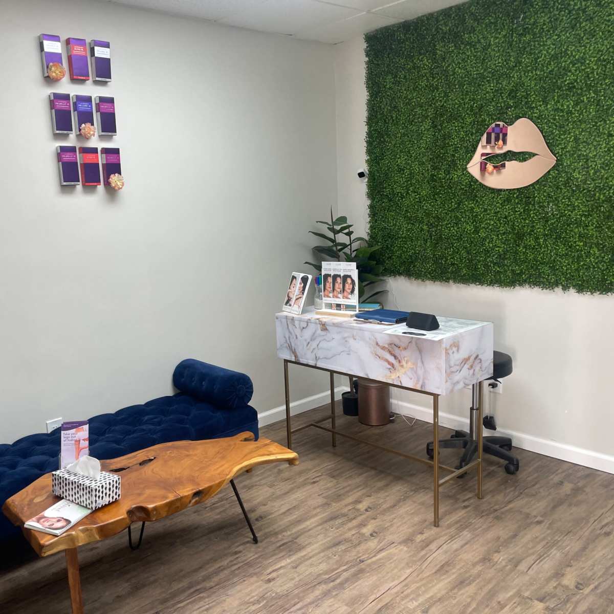 A stylish reception area with a blue velvet couch, a wooden coffee table, and a marble reception desk against a backdrop of green foliage.