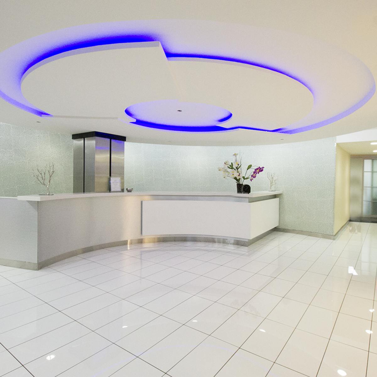 A modern reception area with a curved front desk, bright lighting, and tiled flooring.