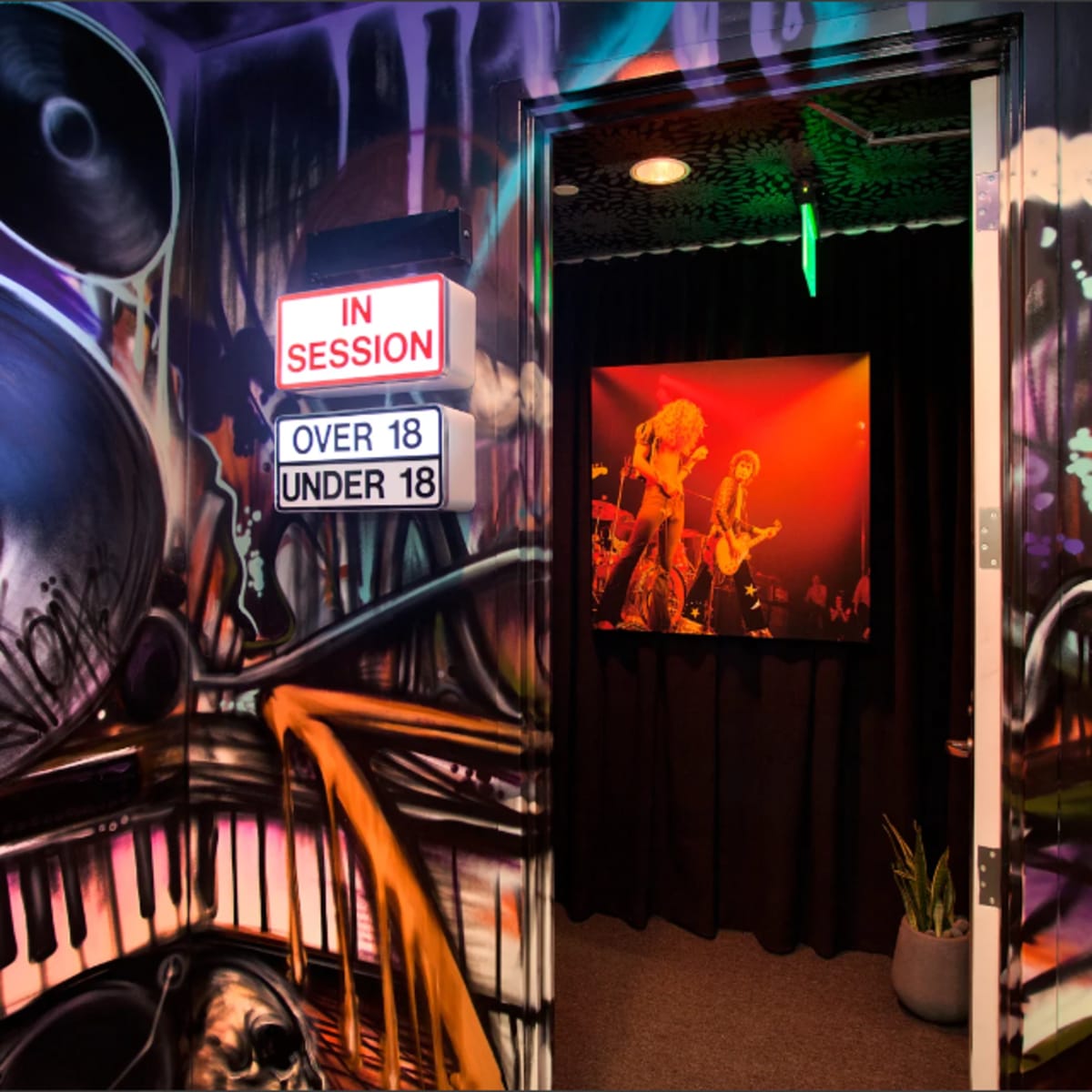 A hallway features vibrant graffiti art of speakers and a piano, with a sign indicating "IN SESSION" and a doorway leading to a performance area.