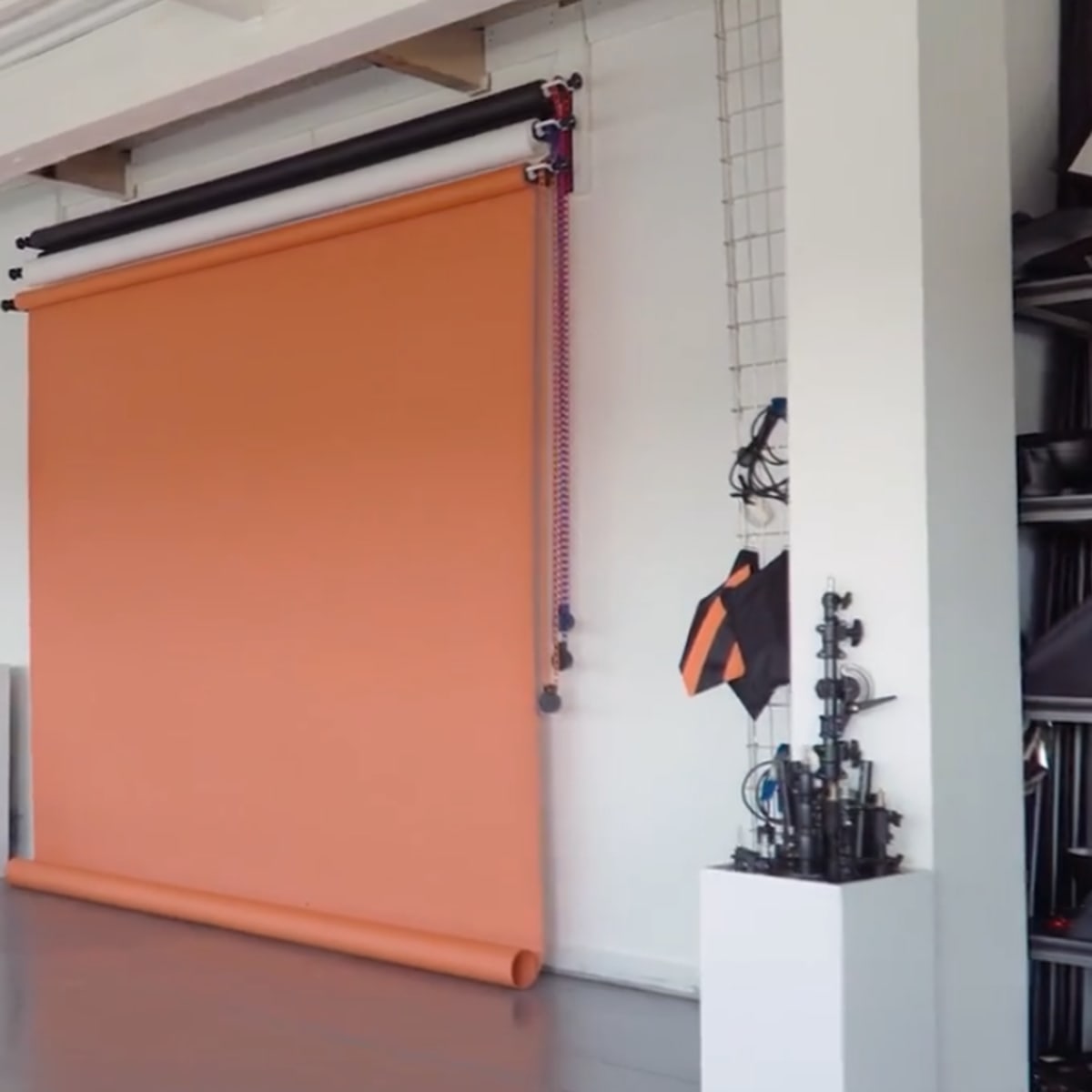 A studio setting featuring an orange backdrop mounted on a wall, a stool, and a set of stairs leading up to it.