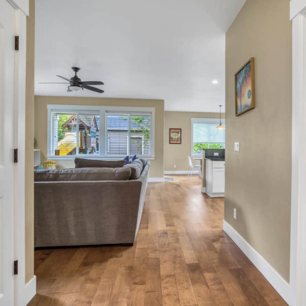 A view from a hallway into a bright living area with a sofa, dining space, and a small bathroom on the left.