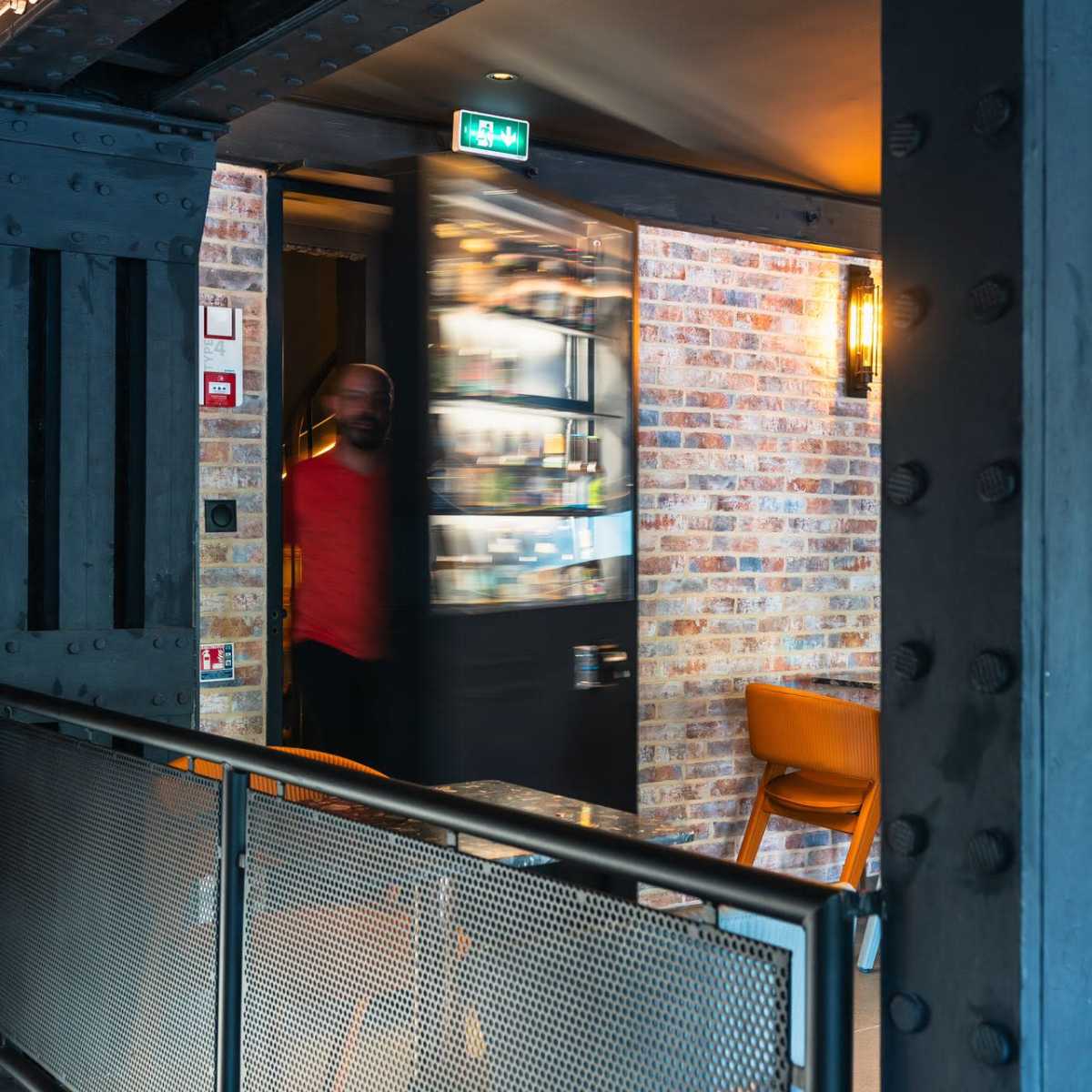 A person exits through a partially opened door in a modern, industrial-style interior.