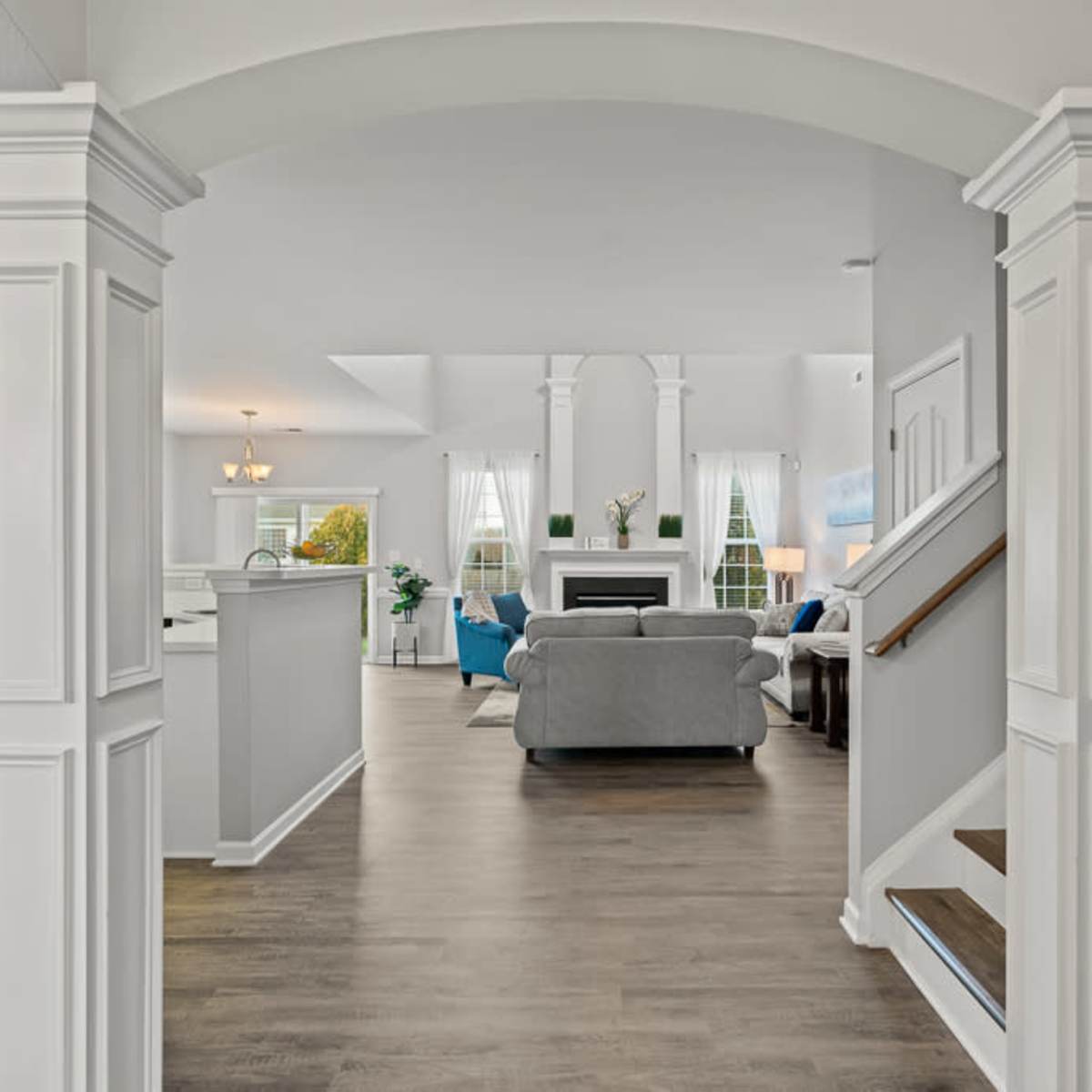 A spacious, welcoming entryway leading into a bright living area with a sofa, a fireplace, and large windows.
