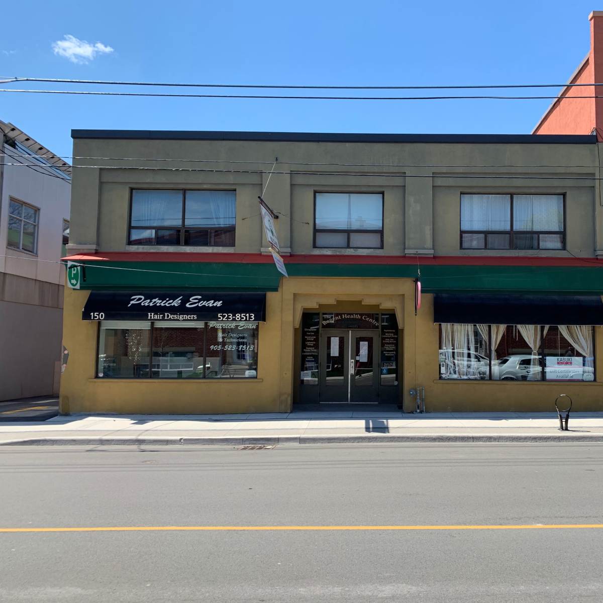 A two-story commercial building with a green facade and a sign for "Patrick Eats Hair Designers" on the left.