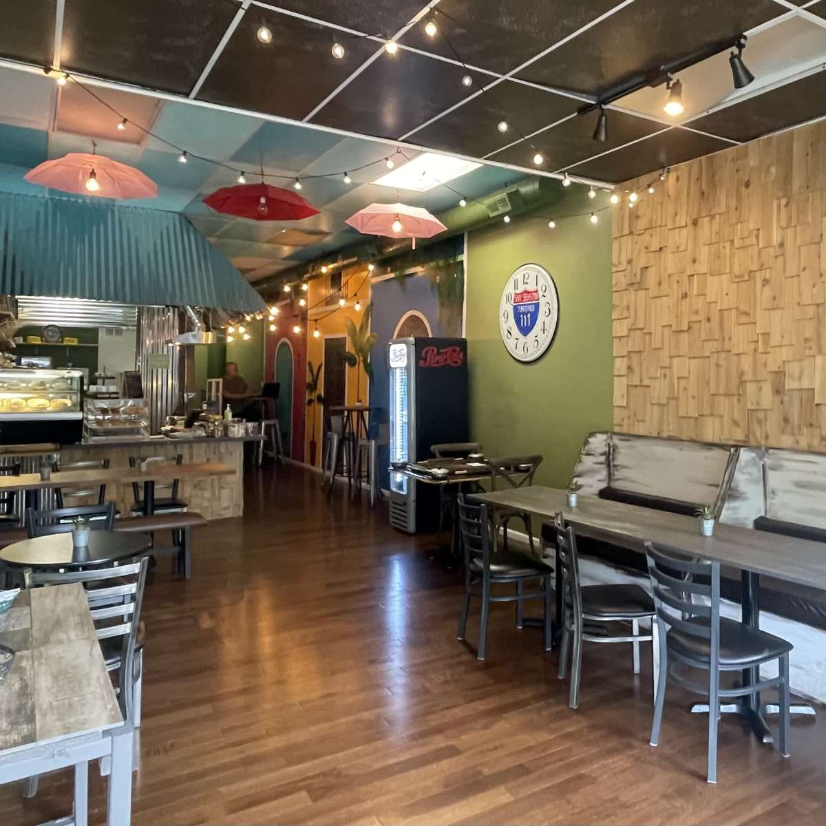 A cozy restaurant interior with wooden floors, green walls, and various seating arrangements, including booths and tables.