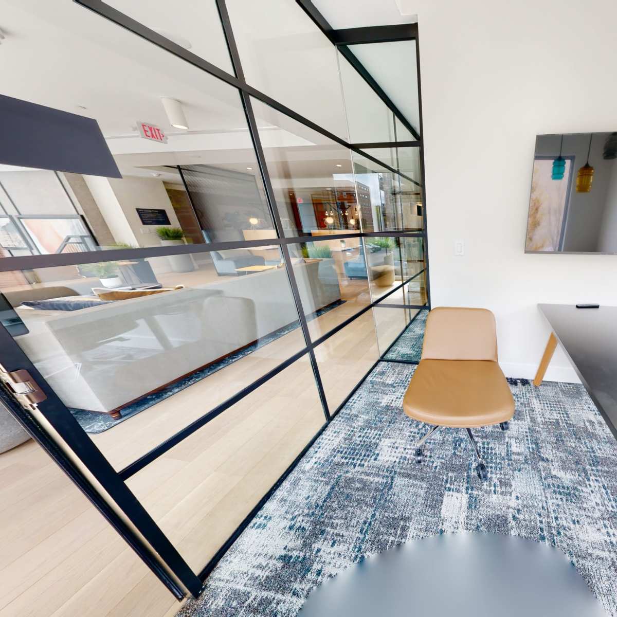 A modern office space featuring a glass-enclosed meeting room, a sleek desk, a chair, and a wall-mounted television.