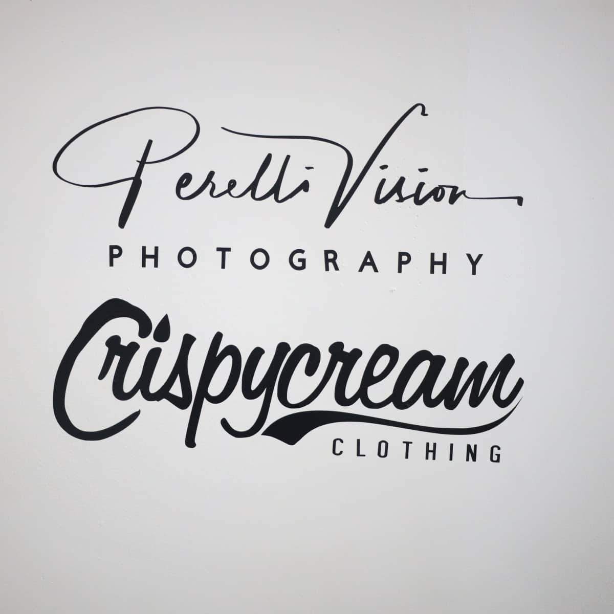 A wall with two business names: "Perelli Vision Photography" and "Crispycream Clothing" displayed in artistic fonts.