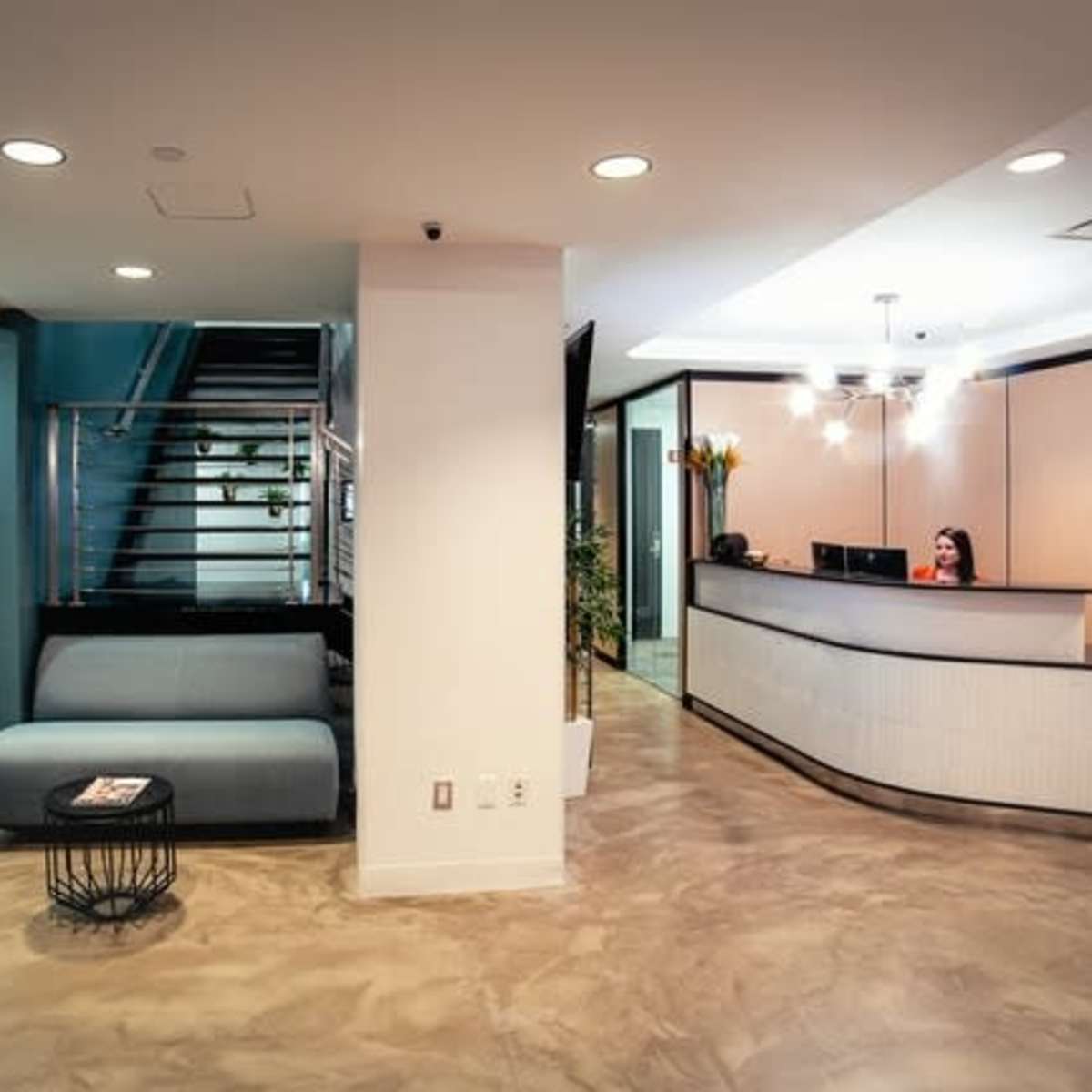 A modern office reception area with a seating space, a glass-walled meeting room, and a reception desk.