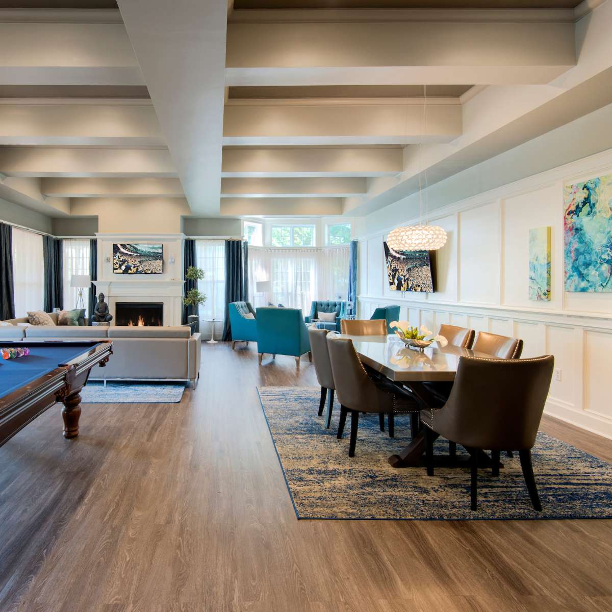A spacious living area featuring a pool table, a dining table, and large windows that allow natural light to fill the room.